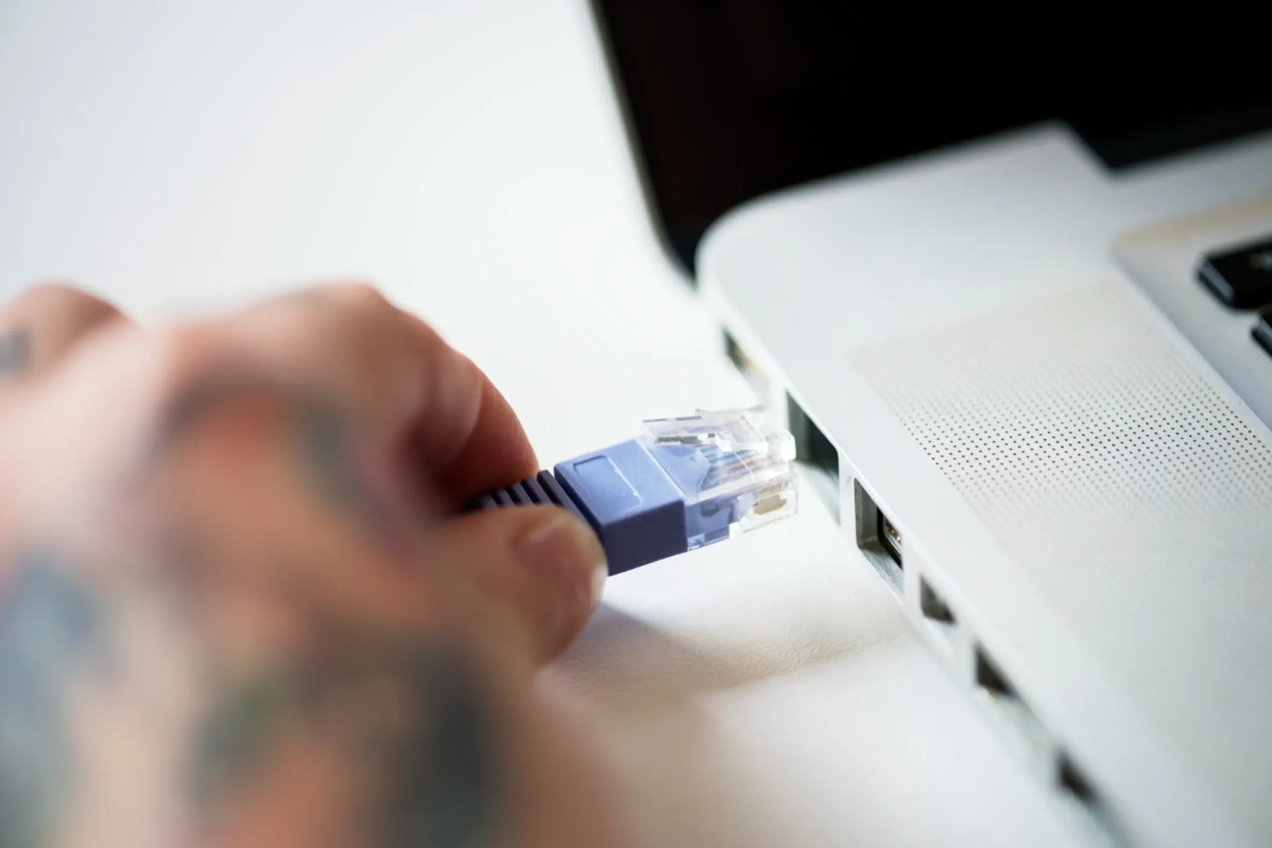 Hand connecting Ethernet cable to laptop