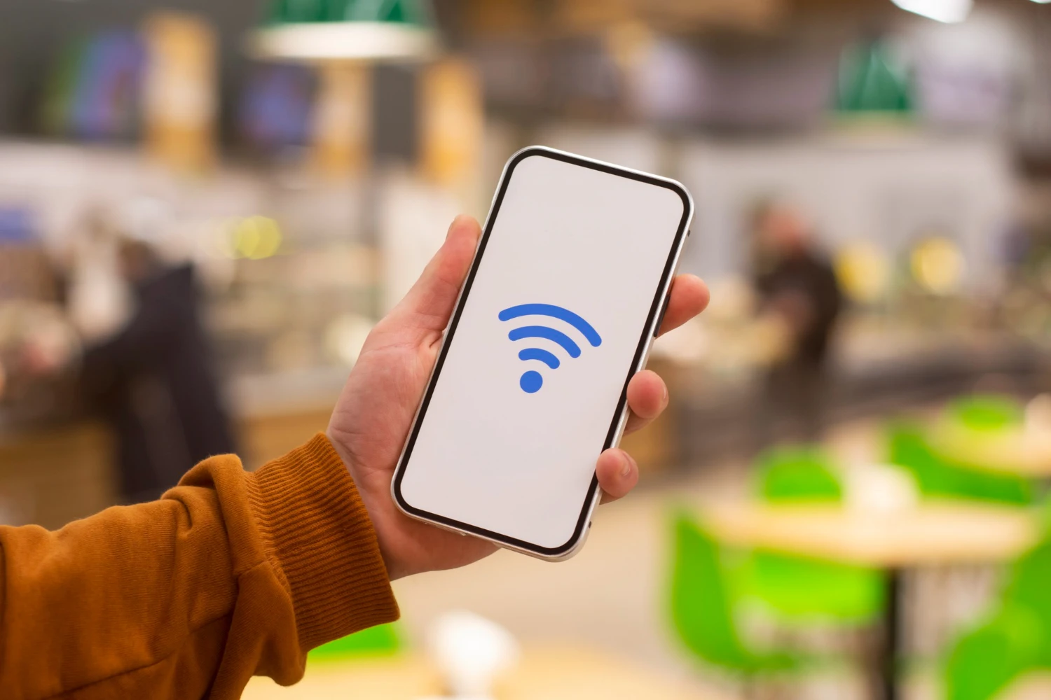 Hand holding smartphone displaying Wi-Fi symbol