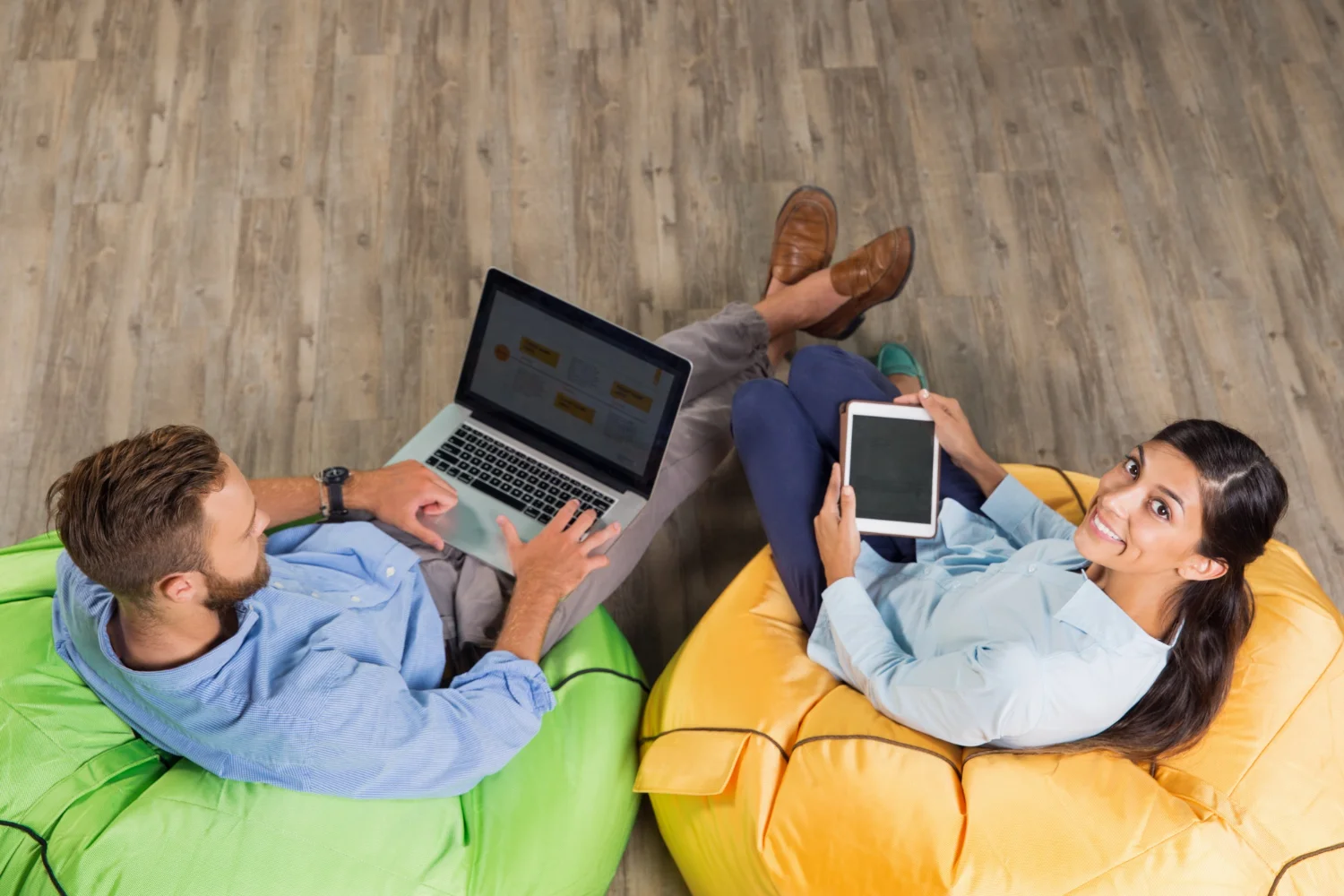 Two people working on devices in bean bags