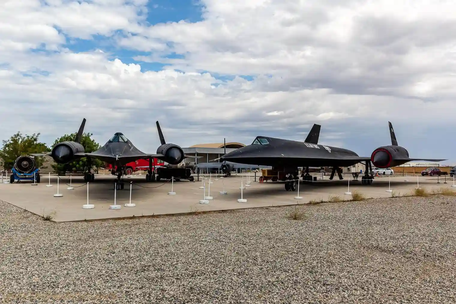 Two black aircraft displayed outdoors under cloudy sky.