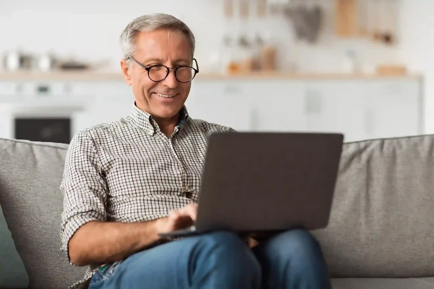Smiling man using a laptop on a couch