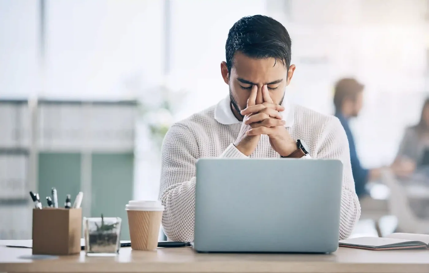 Stressed man working at a laptop in office