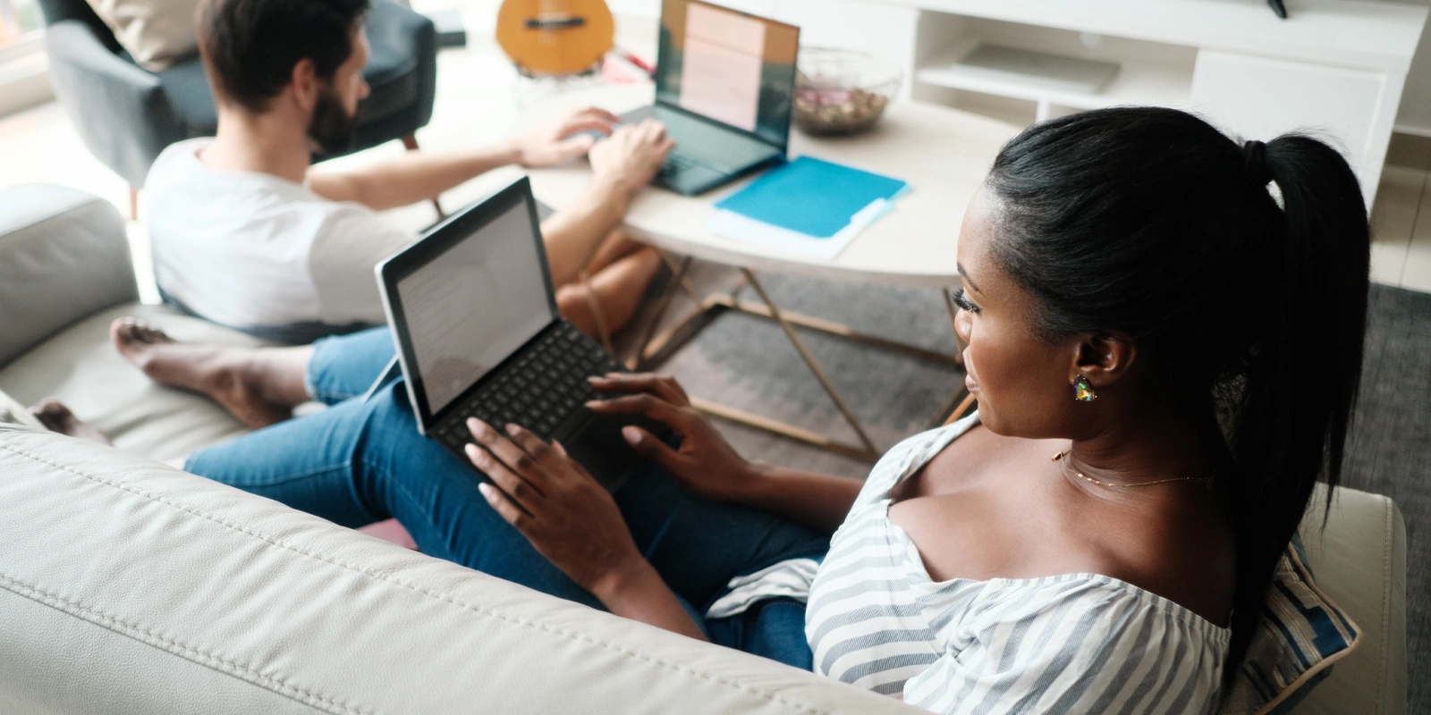 Two individuals working on laptops at home.