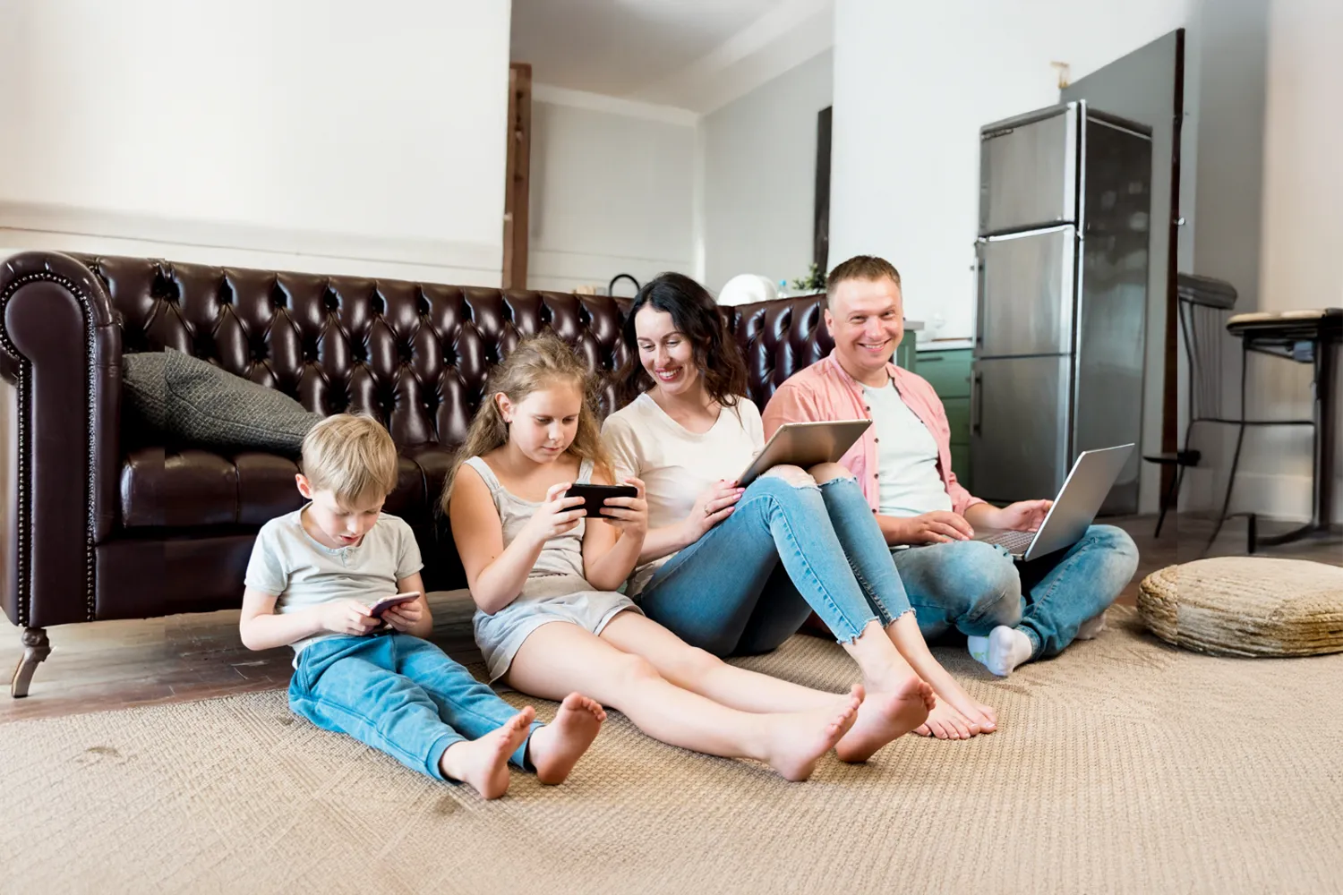 Family enjoying digital devices on living room floor.