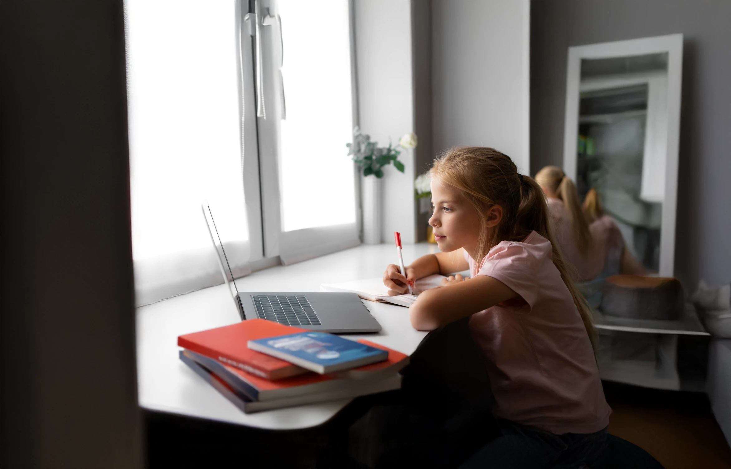Child studying at a desk with a laptop