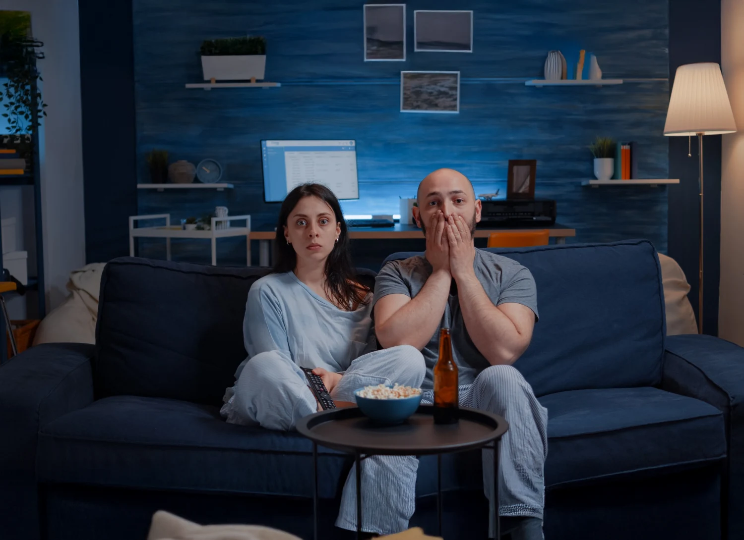 Couple watching a movie, looking surprised.