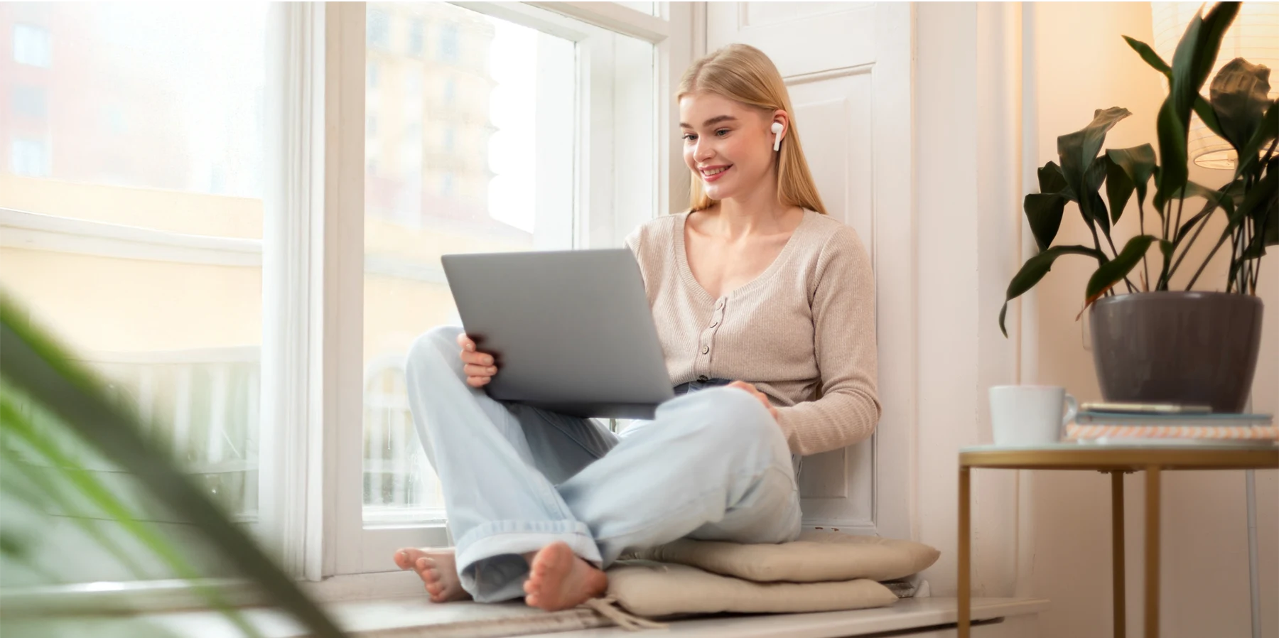 Young woman working on a laptop by the window.
